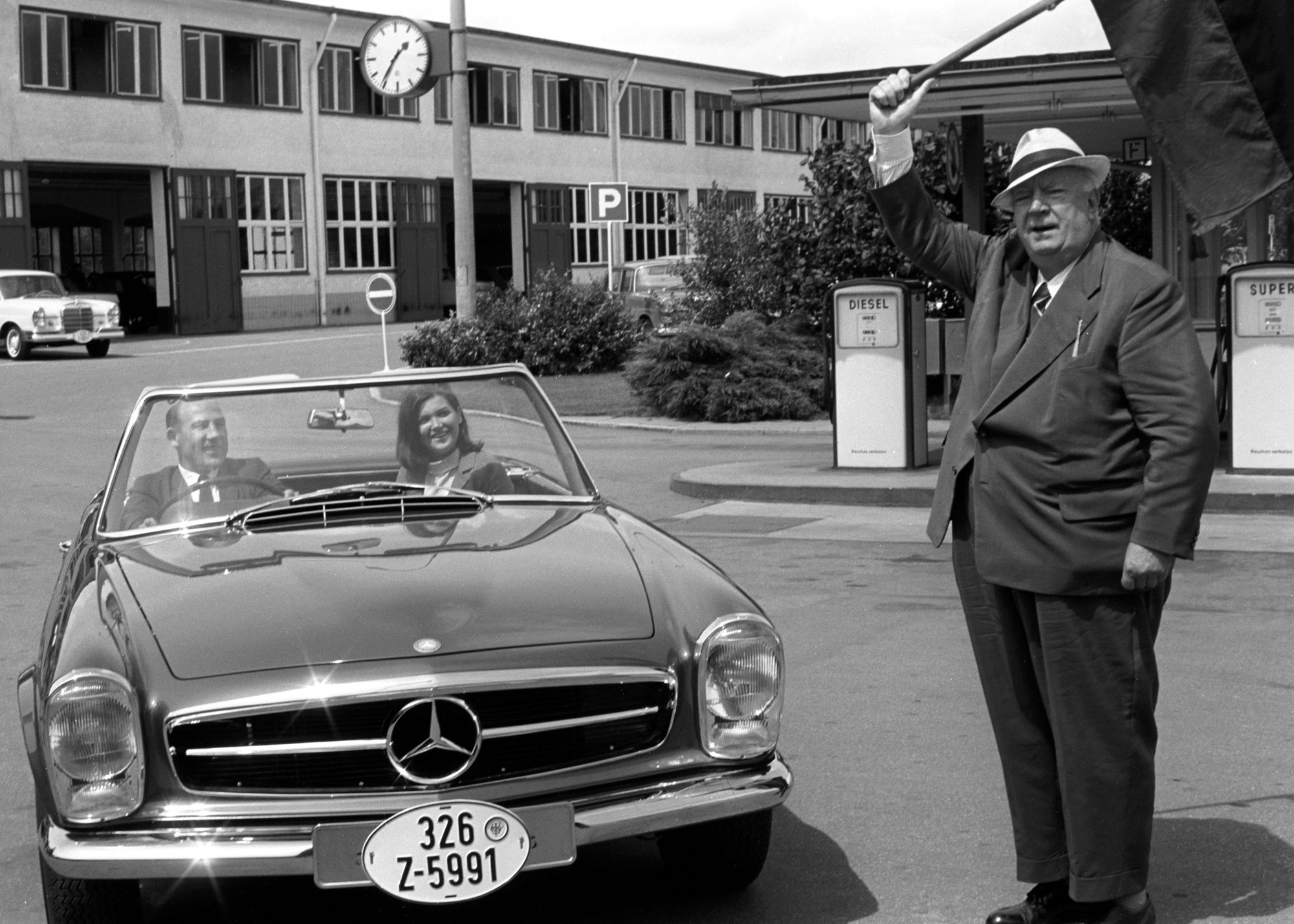Archive black and white photograph of a Pagoda at a factory forecourt with a man waving a flag